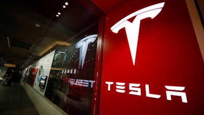 This Feb. 9, 2019, file photo shows a sign bearing the company logo outside a Tesla store in Cherry Creek Mall in Denver. Tesla says it delivered 241,300 electric vehicles in the third quarter in 2021, even as it wrestled with a global shortage of computer chips that has hit the entire auto industry. The Palo Alto, California, company’s sales from July through September beat Wall Street estimates.