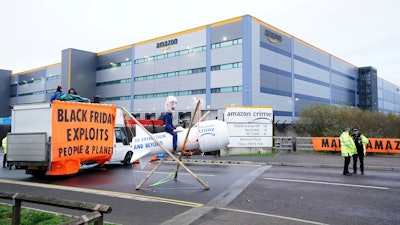 Activists from Extinction Rebellion block the entrance to an Amazon fulfillment center, Tilbury, England, Nov. 26, 2021.