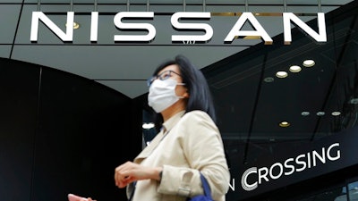 A woman walks the Nissan automaker's showroom in Tokyo Tuesday, May 11, 2021. Nissan reported Tuesday, Nov. 9, 2021, a 54.1 billion yen ($479 million) profit for the July-September quarter, a reversal from the 44 billion yen loss racked up last year, despite the continuing damage from the computer chip sshortage slamming the auto industry.
