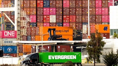 A truck passes a container ship at the Port of Oakland on Tuesday, Oct. 19, 2021, in Oakland, Calif. California farmers say they are having trouble exporting their crops because of delays in the global supply chain. Intense demand for products has led to a backlog of container ships outside the nation's two largest ports along the Southern California coast.