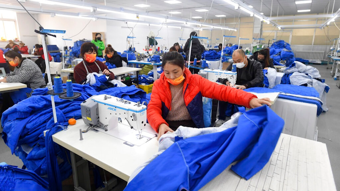 Workers wearing face masks sew fabric in a garment factory in Shenyang in northeastern China's Liaoning Province, Tuesday, Dec. 14, 2021. China reported Wednesday, Dec. 15, 2021, that its economy slowed in November, buffeted by coronavirus outbreaks, weak demand and supply chain disruptions.