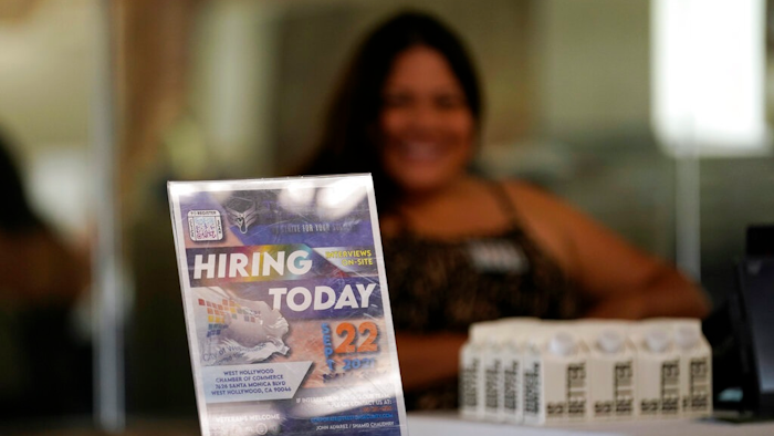 A hiring sign is placed at a booth for prospective employers during a job fair Wednesday, Sept. 22, 2021, in the West Hollywood section of Los Angeles. America’s employers slowed the pace of their hiring in November, adding a still-solid 210,000 jobs, the fewest in nearly a year. Friday, Dec. 3, report from the Labor Department also showed that the unemployment rate fell sharply to 4.2% from 4.6%.