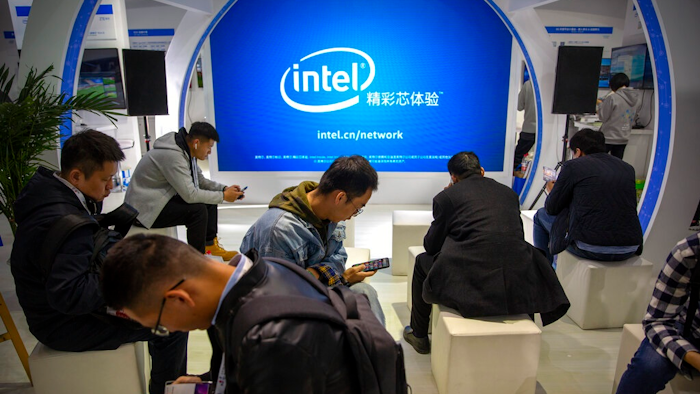 Attendees look at their smartphones at a booth from chipmaker Intel at the PT Expo in Beijing on Oct. 31, 2019. Intel Corp. apologized Thursday, Dec. 23, 2021 for asking suppliers to avoid sourcing goods from Xinjiang after the chipmaker became the latest foreign brand to face the fury of state media regarding the region, where the ruling Communist Party is accused of widespread abuses.