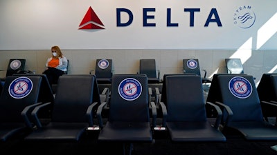 A passenger wears a face mask as she waits in a socially-distance area for a Delta Airlines flight, Wednesday, Feb. 3, 2021, at Hartsfield-Jackson International Airport in Atlanta. Delta Airlines is reversing course on its outlook for the fourth quarter, now saying that it anticipates a profit instead of a loss. The company said Thursday, Dec. 16, that it now foresees an adjusted profit of approximately $200 million for the period.