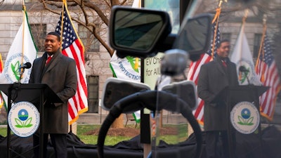 Environmental Protection Agency (EPA) Administrator Michael Regan is reflected in an electronic vehicle as it charges as he speaks during an event to announce the Agency's final rule for federal greenhouse gas (GHG) emissions standards for light duty vehicles, Monday, Dec. 20, 2021, outside the EPA Headquarters, in Washington.