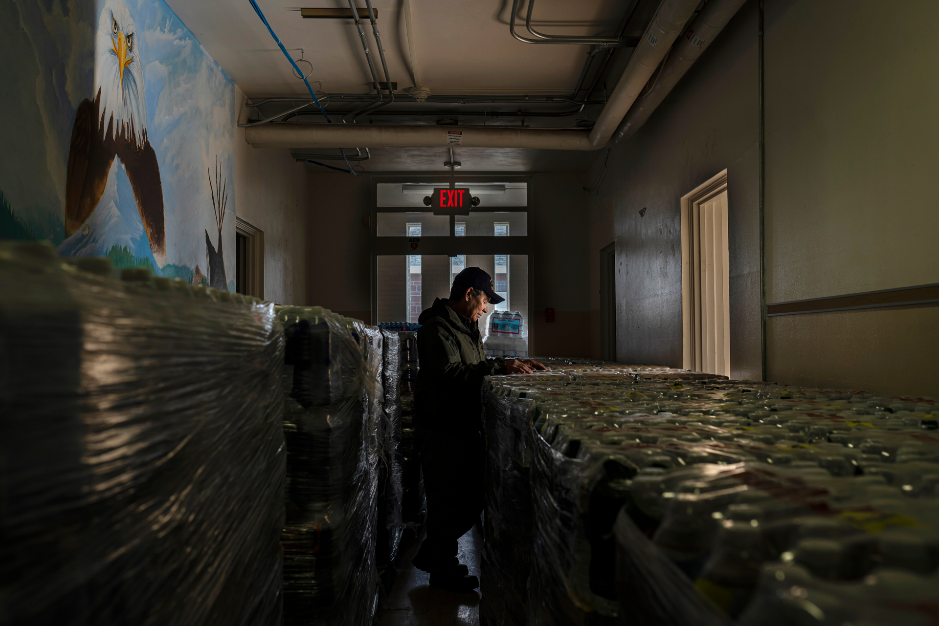 Dan Martinez, emergency manager for the Confederated Tribes of Warm Springs, pauses in the hallway of a storage building filled with donated water on Tuesday, Dec. 7, 2021, in Warm Springs, Ore. “The infrastructure bill brought joy to my heart because now it gives me hope — hope that it’s going to be repaired,” said Martinez, the tribes’ emergency manager.