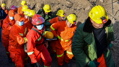 In this photo released by China's Xinhua News Agency, rescuers evacuate a trapped miner from a flooded coal mine in Xiaoyi city in northwestern China's Shanxi Province, Friday, Dec. 17, 2021. Crews have safely rescued 20 of 21 Chinese coal miners trapped inside a flooded shaft, with one still missing.