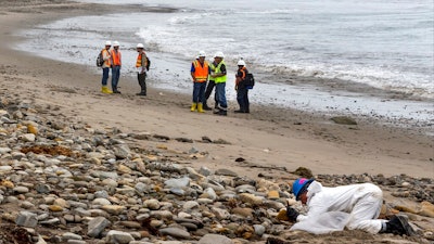 Shoreline Cleanup Assessment Technique team members, left, evaluate oil coverage as a hand crew worker scraps areas affected by an oil spill at Refugio State Beach, north of Goleta, Calif., on Wednesday, June 10, 2015. A proposal to replace a pipeline near Santa Barbara that was shut down in 2015 after causing California's worst coastal oil spill in 25 years is inching through a government review, even as the state moves toward banning gas-powered vehicles and oil drilling.