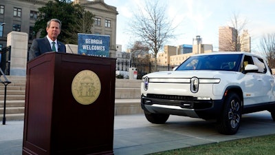 Georgia Gov. Brian Kemp is flanked by a Rivian electric truck announces that the electric truck maker plans to build a $5 billion battery and assembly plant east of Atlanta projected to employ 7,500 workers, Thursday, Dec. 16, 2021, in Atlanta.