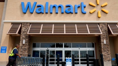 In this May 9, 2013, file photo, a worker pushes shopping carts in front of a Wal-Mart store in La Habra, Calif. Retail giant Walmart illegally dumps more 1 million batteries, aerosol cans of insect killer and other products, toxic cleaning supplies, electronic waste, latex paints and other hazardous waste into California landfills each year, state prosecutors alleged in a lawsuit filed Monday, Dec. 20, 2021.