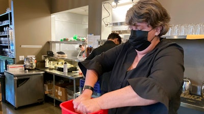 Folsom Vice Mayor Sarah Aquino wrings out a rag before cleaning a table at Back Bistro in Folsom, Calif., on Tuesday, Nov. 23, 2021. Aquino is an insurance broker. But she took a part-time job at one of her favorite local restaurants because they were struggling to hire people. Employers have reported a shortage of workers to meet demand as more people return to normal habits following the disruption of the coronavirus pandemic. Aquino sees it as her civic duty to help out local businesses.