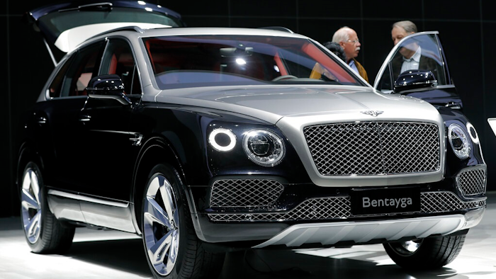 People stand at a Bentley Bentayga SUV car during the annual shareholders meeting of the Volkswagen AG in Hannover, Germany, Wednesday, May 10, 2017. Luxury automaker Bentley says it is pouring billions into upgrading manufacturing to accelerate its electric vehicle development plan, joining other auto brands shifting away from gasoline engines. U.K.-based Bentley Motors said Wednesday, Jan. 26, 2022 that it's investing 2.5 billion pounds ($3.4 billion) into sustainability efforts over the next decade.