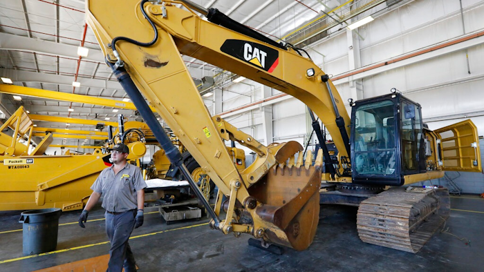A Puckett Machinery Company technician walks past a new heavy duty Caterpillar excavator that awaits modification at Puckett Machinery Company in Flowood, Miss. Sept. 18, 2019. Caterpillar continued to see a healthy surge in sales during its fourth quarter of 2022, as the economy strengthens. Sales climbed 23% to $13.8 billion.