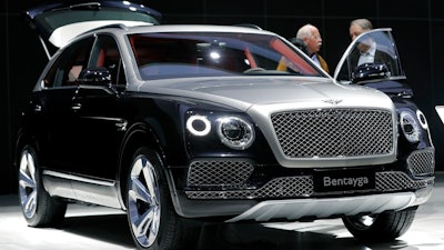 People stand at a Bentley Bentayga SUV car during the annual shareholders meeting of the Volkswagen AG in Hannover, Germany, Wednesday, May 10, 2017. Luxury automaker Bentley says it is pouring billions into upgrading manufacturing to accelerate its electric vehicle development plan, joining other auto brands shifting away from gasoline engines. U.K.-based Bentley Motors said Wednesday, Jan. 26, 2022 that it's investing 2.5 billion pounds ($3.4 billion) into sustainability efforts over the next decade.