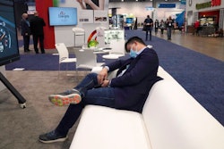 An attendee rests on a couch during the CES tech show Thursday, Jan. 6, 2022, in Las Vegas.