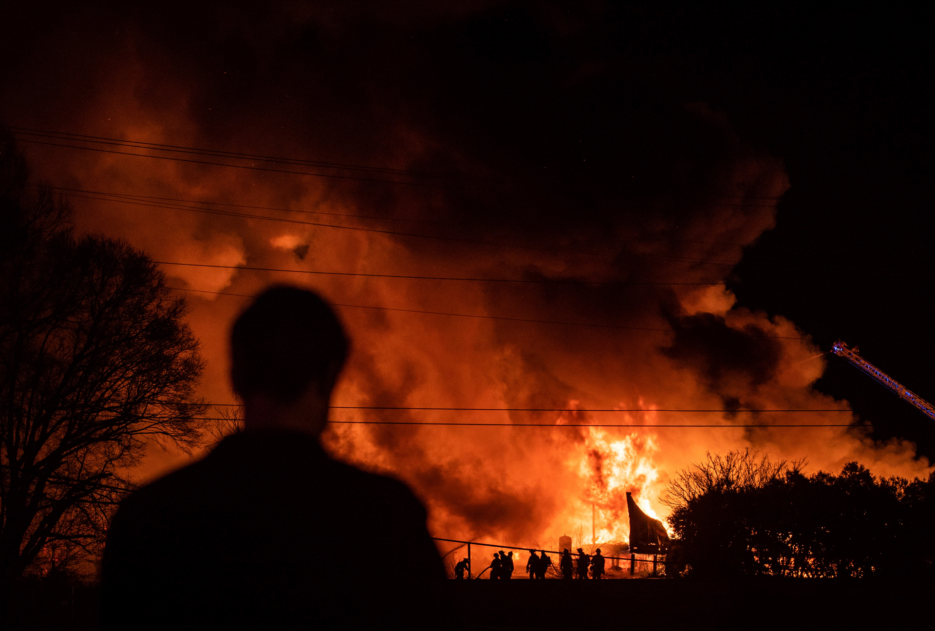 A bystander watches as Winston-Salem firefighters battle a structure fire at Weaver Fertilizer Co. on Monday, Jan. 31, 2022, in Winston-Salem, N.C.