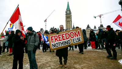 Don Stephens, 65, a retired graphic designer, holds a sign on Parliament Hill to support trucks lined up in protest of COVID-19 vaccine mandates and restrictions in Ottawa, Ontario, on Feb. 12, 2022.