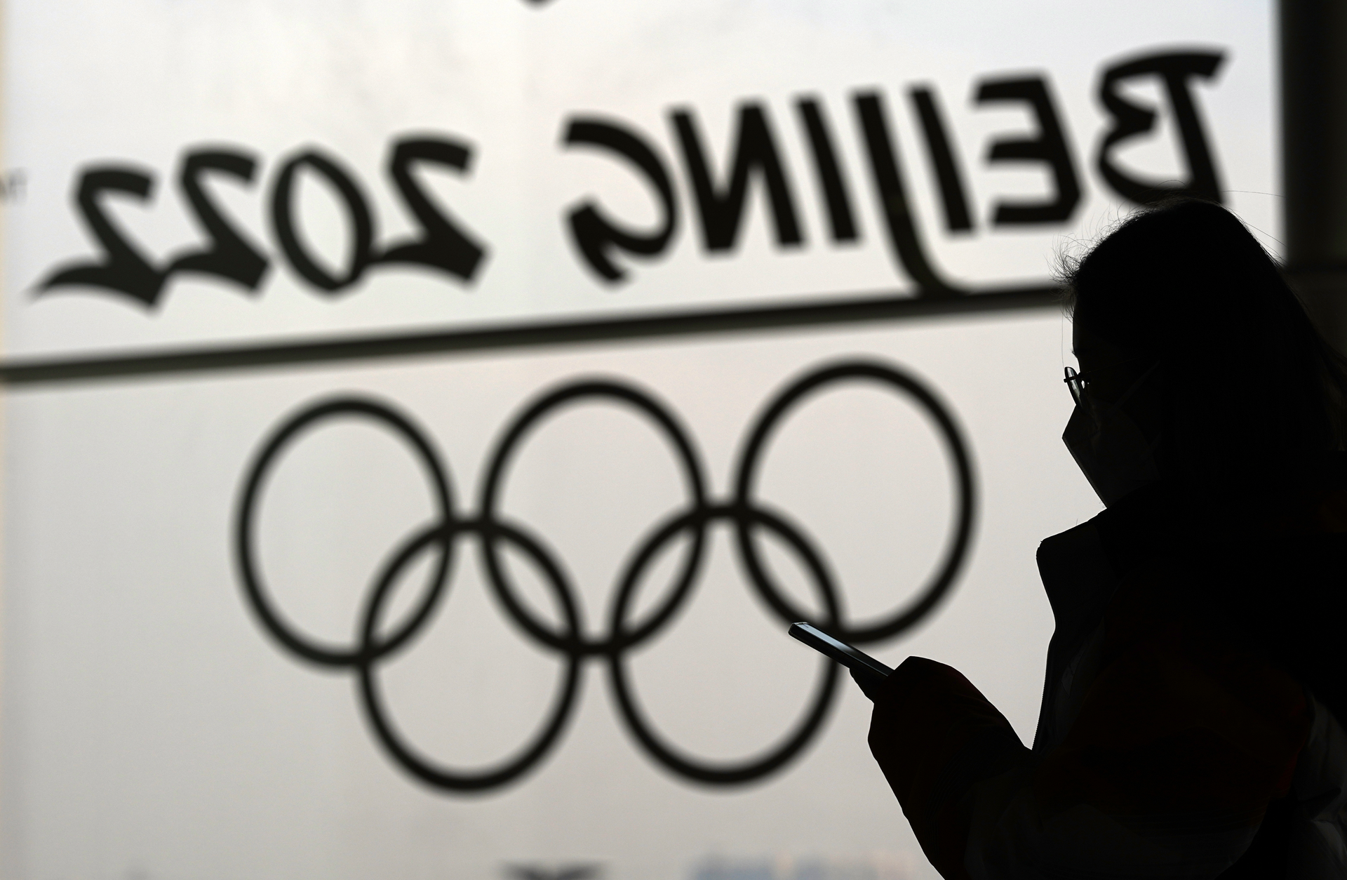 A woman looks at her phone inside the main media center for the 2022 Winter Olympics, Beijing, Jan. 18, 2022.
