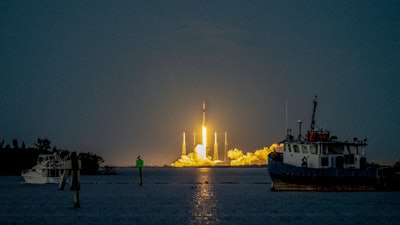 A SpaceX Falcon 9 rocket launches from Florida. The image shows the rocket clearing the lightning arrestor towers at dusk.