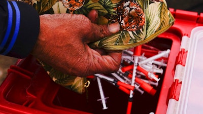 Keith Lewis disposes of used syringes at a needle exchange run by Camden Area Health Education Center in Camden, N.J., Thursday, Feb. 24, 2022. Four companies involved in the opioid industry are finalizing settlements over the addiction crisis in the U.S. in deals that could total $26 billion over 18 years.