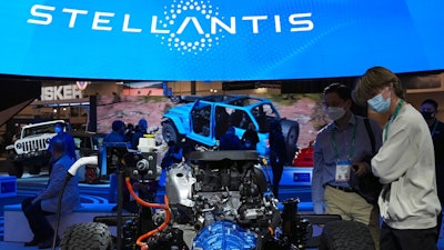 People look at the charging technology from the Jeep Wrangler 4xe at the Stellantis booth during the CES tech show Thursday, Jan. 6, 2022, in Las Vegas. Automaker Stellantis said Wednesday, Feb. 23, 2022 that it made 13.4 billion euros ($15.2 billion) in its first year after it was formed from the merger of Fiat Chrysler Automobiles and PSA Group.