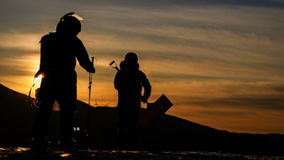 Workers arrive at the sunrise before the women's slopestyle finals at the 2022 Winter Olympics, Sunday, Feb. 6, 2022, in Zhangjiakou, China.