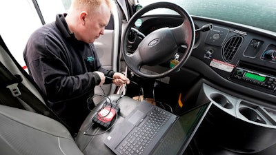 Brian Hohmann, mechanic and owner of Accurate Automotive, in Burlington, Mass., attaches a diagnostics scan tool, center left, to a vehicle and a laptop computer, below, Tuesday, Feb. 1, 2022, in Burlington. The diagnostics scan tool sends information from the vehicle's computer to the laptop so a mechanic can view information about the vehicle's performance.