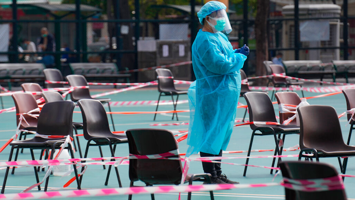 A health worker wearing protective gear waits for residents to be tested for the coronavirus at a temporary testing center in Hong Kong on Feb. 28, 2022.