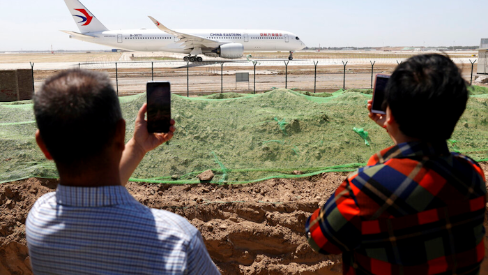 Residents watch as a China Eastern passenger jet prepares to take off on a test flight from the new Beijing Daxing International Airport on Monday, May 13, 2019. State media are reporting a Chinese airliner from China Eastern with 133 people on board crashed in the southern province of Guangxi on Monday, sparking a mountainside fire.
