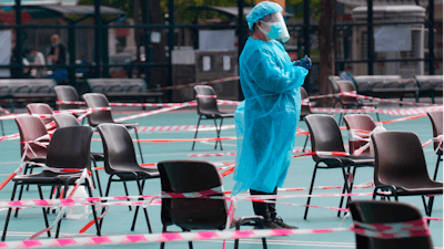 A health worker wearing protective gear waits for residents to be tested for the coronavirus at a temporary testing center in Hong Kong on Feb. 28, 2022.