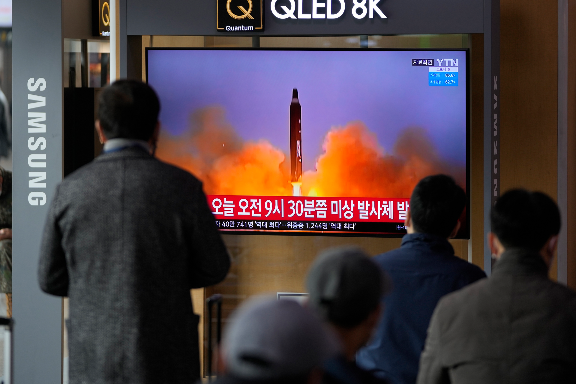 People watch a TV screen showing a news program reporting about North Korea's missile with file footage, Seoul, March 16, 2022.