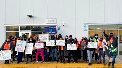 Amazon workers hold sigs after walking out of the Amazon DMD9 delivery station in Upper Marlboro, Md., on March 16, 2022.