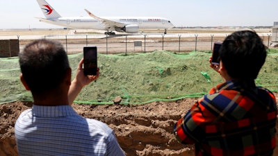 Residents watch as a China Eastern passenger jet prepares to take off on a test flight from the new Beijing Daxing International Airport on Monday, May 13, 2019. State media are reporting a Chinese airliner from China Eastern with 133 people on board crashed in the southern province of Guangxi on Monday, sparking a mountainside fire.