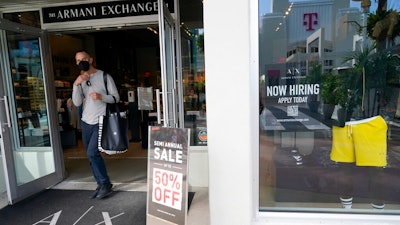 For sale and hiring signs are displayed at an Armani Exchange store, Friday, Jan. 21, 2022, in Miami Beach, Fla.