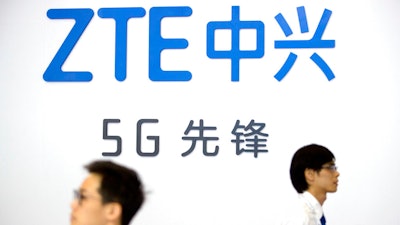 Visitors walk past a display from Chinese technology firm ZTE at the PT Expo in Beijing, Sept. 26, 2018. ZTE Corp. said Wednesday, March 23, 2022, a U.S. judge has allowed a probation period to end after the telecom equipment maker was nearly destroyed in a clash with Washington over its dealings with Iran and North Korea.