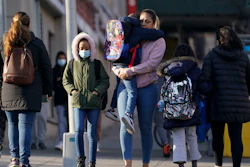 Children and their caregivers arrive for school in New York, Monday, March 7, 2022. COVID cases are starting to rise again in the United States, with numbers up in most states and up steeply in several. One expert says he expects more of a “bump” than the monstrous surge of the first omicron wave, but another says it’s unclear how high the curve will rise and it may be more like a hill.