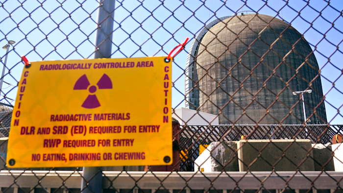 A sign warning of radioactive materials is seen on a fence around a nuclear reactor containment building on Monday, April 26, 2021, a few days before it stopped generating electricity at Indian Point Energy Center in Buchanan, N.Y. The Biden administration is launching a $6 billion effort to save nuclear power plants at risk of closing, citing the need to continue nuclear energy as a carbon-free source of power that helps to combat climate change.