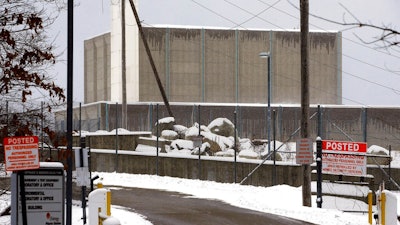 A no trespassing sign is posted near the entrance to the Pilgrim Nuclear Power Station, at rear, Thursday, Feb. 28, 2019, in Plymouth, Mass. One million gallons of radioactive water is contained inside the former nuclear power plant along Cape Cod Bay. The plant's owner, Holtec International, is considering treating the water and discharging it into the bay. Local residents, shell fishermen and politicians disapprove of the plan.