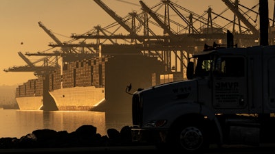 A truck arrives to pick up a shipping container near vessels moored at Maersk APM Terminals Pacific at the Port of Los Angeles, Nov. 30, 2021.