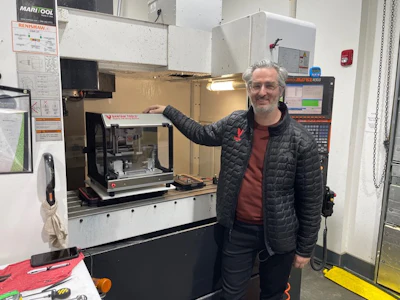Bantam Tools CEO Bre Pettis stands with the Bantam Tools Desktop CNC Milling Machine inside of another industrial-size CNC machine.