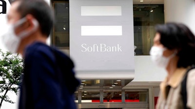 Passersby move past a SoftBank shop in Tokyo, Thursday, May 12, 2022. Japanese technology company SoftBank Group reported Thursday it has dropped into losses as the value of its investments declined.