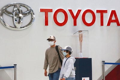 People walk past the logo of Toyota at a showroom in Tokyo Monday, Oct. 18, 2021. Toyota's profit declined 31% in the January-March 2022 quarter from the year before, but the Japanese automaker still wrapped up a year of record earnings.