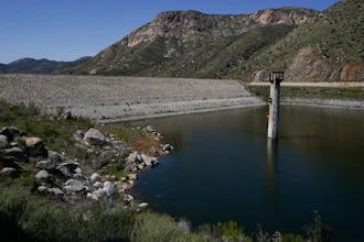 The dam at El Capitan Reservoir is seen Friday, April 8, 2022, in Lakeside, Calif. Constructed four generations ago, the massive rock and clay dam is capable of storing over 36 billion gallons of water — enough to supply every resident in San Diego for most of a year. Today, it's three-quarters empty — intentionally kept low because of concerns it could fail under the strain of too much water.