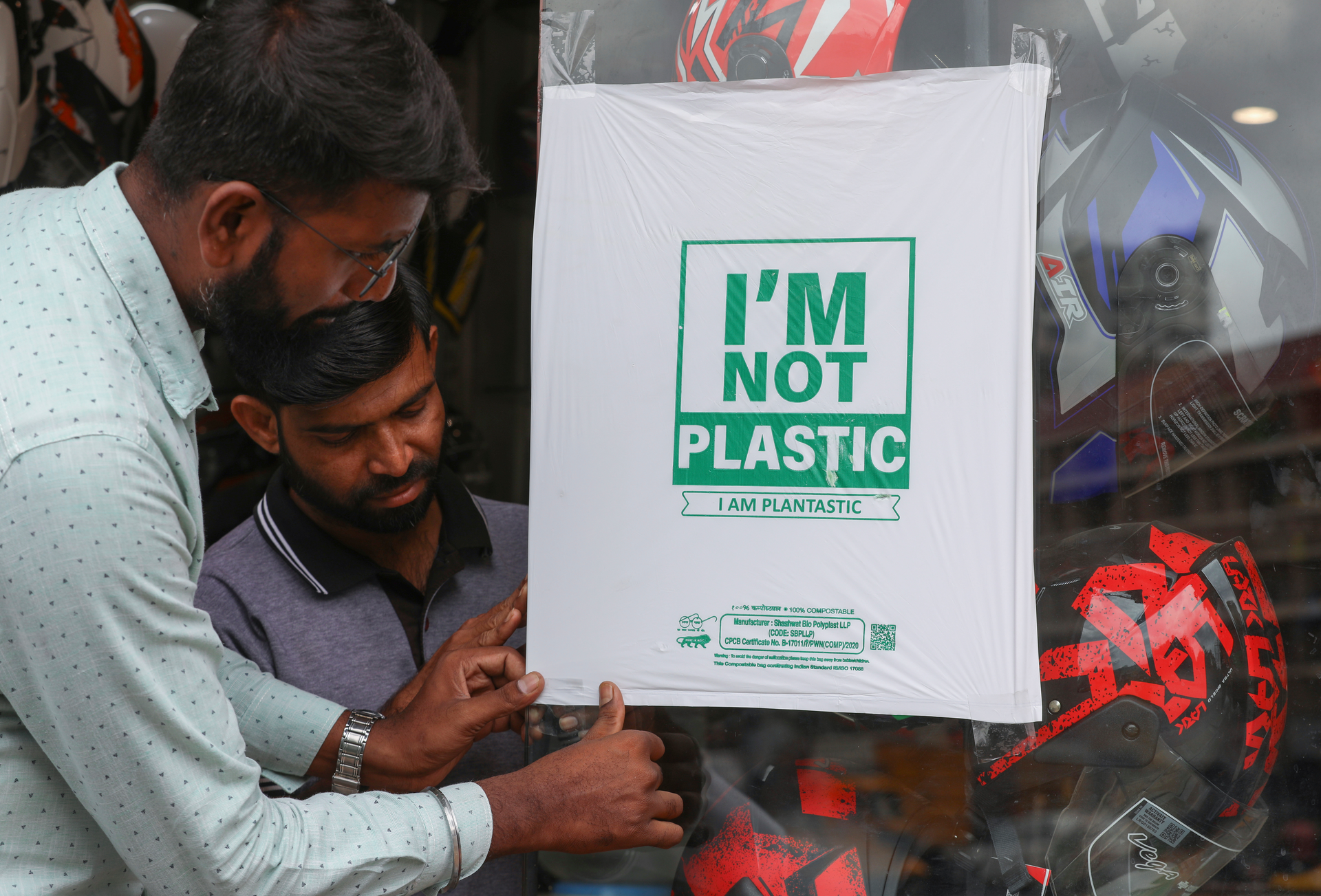 Workers paste degradable plastic substitute material on glass, Hyderabad, India, June 30, 2022.