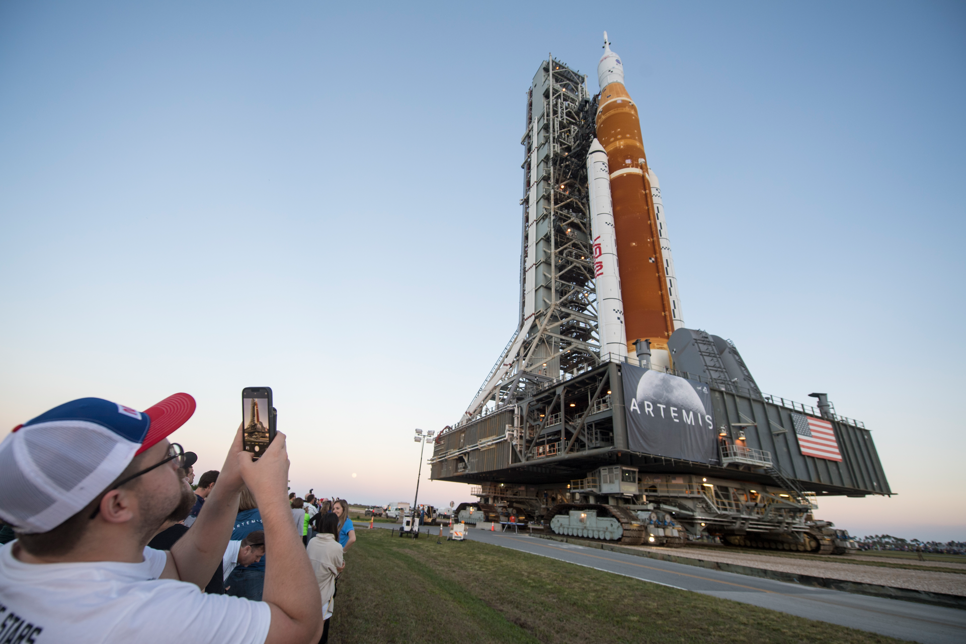 Invited guests and NASA employees take photos as NASA's Space Launch System (SLS) rocket with the Orion spacecraft aboard is rolled out of High Bay 3 of the Vehicle Assembly Building for the first time, at the Kennedy Space Center in Cape Canaveral, Fla., Thursday, March 17, 2022. On Wednesday, July 20, 2022, the 53rd anniversary of the Apollo 11 moon landing, NASA said it’s shooting for a late August test launch of its giant, new moon rocket.