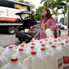 Vanessa Correa, left, and Gigi Fiske, right, pass out gallons of milk at a food distribution held by the Farm Share food bank, Wednesday, July 20, 2022, in Miami. Long lines are back at food banks around the U.S. as working Americans overwhelmed by inflation turn to handouts to help feed their families.