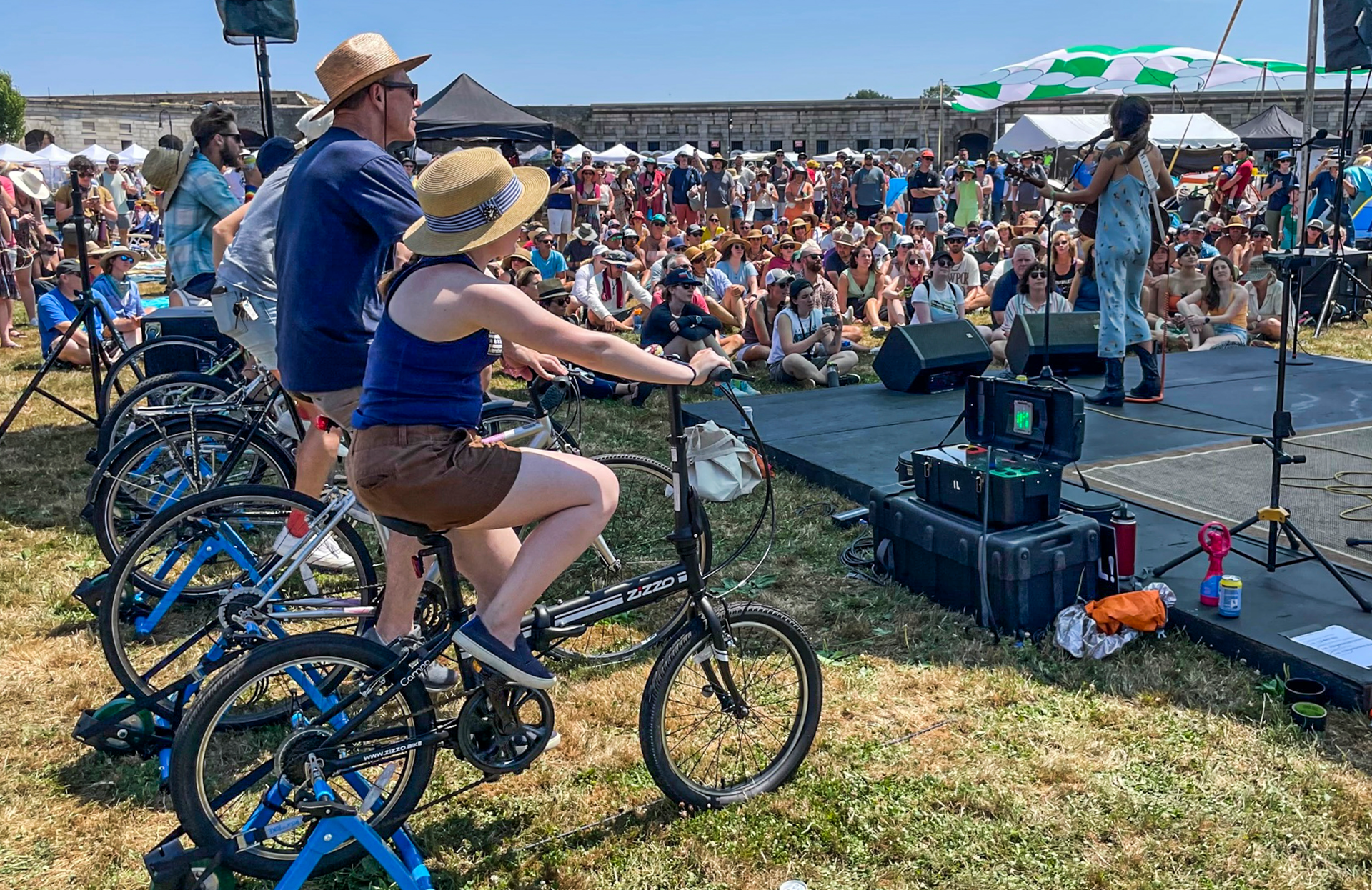 Madi Diaz, right, performs at the Newport Folk Festival's bike stage, powered in part by festivalgoers on stationary bicycles, left, Friday, July 22, 2022, in Newport, R.I.