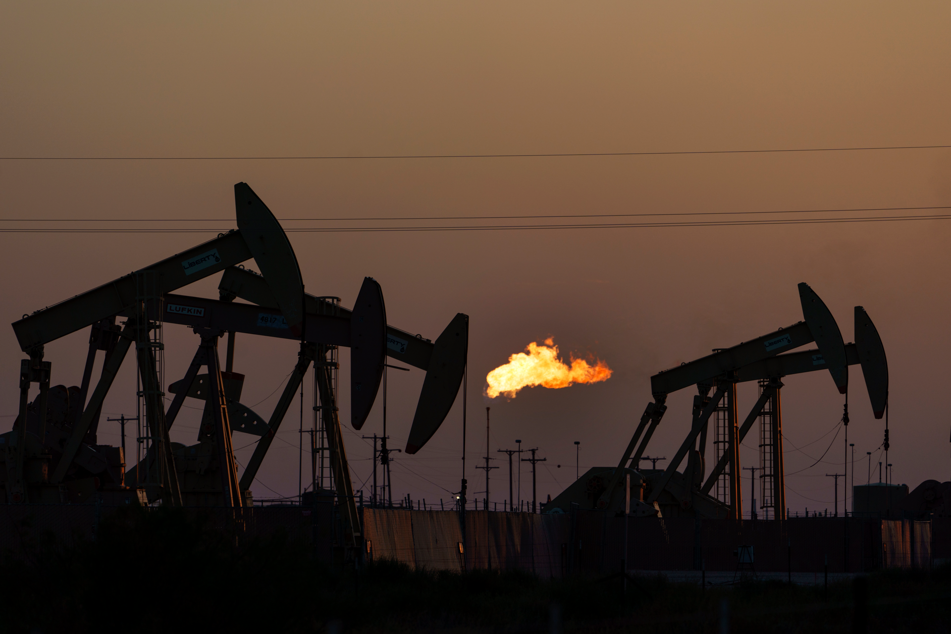 A flare burns off methane and other hydrocarbons as oil pumpjacks operate in the Permian Basin in Midland, Texas, Tuesday, Oct. 12, 2021. Massive amounts of methane are venting into the atmosphere from oil and gas operations across the Permian Basin, new aerial surveys show. The emission endanger U.S. targets for curbing climate change.