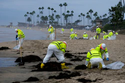 Workers in protective suits clean the contaminated beach in Corona Del Mar after an oil spill off the Southern California coast, on Oct. 7, 2021. The Orange County Board of Supervisors on Tuesday, July 26, 2022, agreed to accept a proposed claim settlement with Amplify Energy Corp, the owner of an underwater oil pipeline that spilled some 25,000 gallons of crude into the ocean.