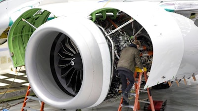 A Boeing employee works on the engine of a 737 MAX on the final assembly line at Boeing's Renton plant, June 15, 2022 in Renton, Wash. Delta is ordering 100 of Boeing's 737 Max 10 airplanes, with an option to purchase 30 more, as the airline looks to keep up with surging travel demand. Delta Air Lines said Monday, July 18, 2022 that the airplanes, which can seat up to 230 people, will reduce fuel use and emissions by 20-30% compared to those it replaces.